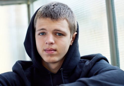young boy with black hood on looking directly at the camera with a sad expression. 
Sexual violence awareness week 