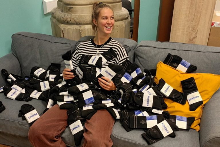Charlotte sat on grey sofa covered in hundreds of socks