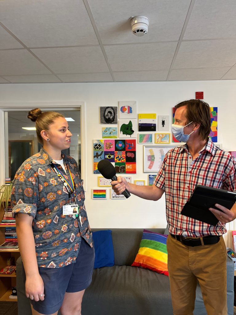 Eli Adi, youth worker, is interviewed by a man holding a microphone