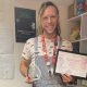 Joshana holding a certificate and glass award