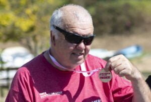 Paul's project worker Geordie smiling holding up a medal after completing a sponsored walk for YMCA DownsLink Group