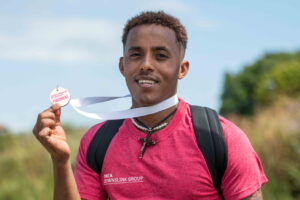 Temesgen smiling holding his medal at the end of the DownsLink Challenge