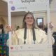 tabs, volunteer photographer, holds a board up that looks like an instagram post and is smiling