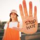 girl holding her hand out. on hand is written stop hate.