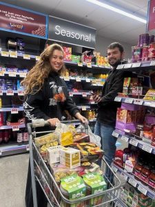 two people filling a trolley in a supermarket