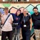 group of 5 people, men and women of various ages, standing in front of a wall with filming equipment