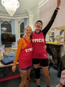 2 women smiling and cheering in branded YMCA running vests