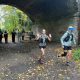 two female runners under an archway with supporters in the background