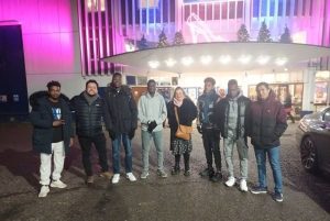 group of diverse people standing outside the Yvonne Arnaud Theatre at night