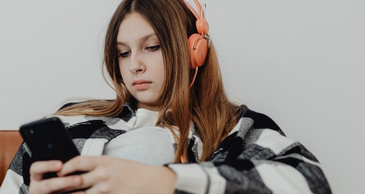 Young person with headphones on looking a mobile phone