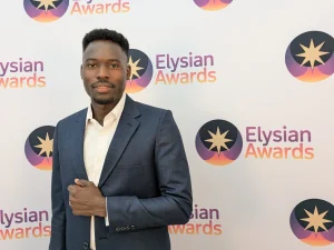 Abdullah stands in front of Elysian Awards branded background