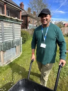 man in garden with wheelbarrow, smiling
