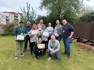 group of people posing outside with certificates