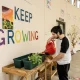 young man watering plants in front of a 'keep growing' mural