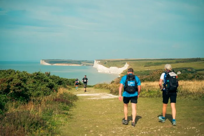 hikers on the south coast trail walking towards the Seven Sisters cliffs
