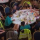 children and their teachers sat around a round table covered in crayons and papers