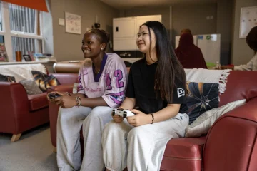 Two young women gaming at YMCA DownsLink Group accommodaation