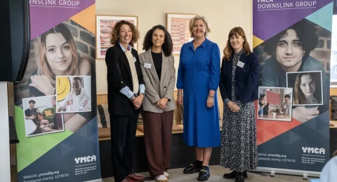 four women stood in front of YMCA DownsLink Group branded banners