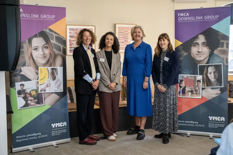 four women stood in front of YMCA DownsLink Group branded banners