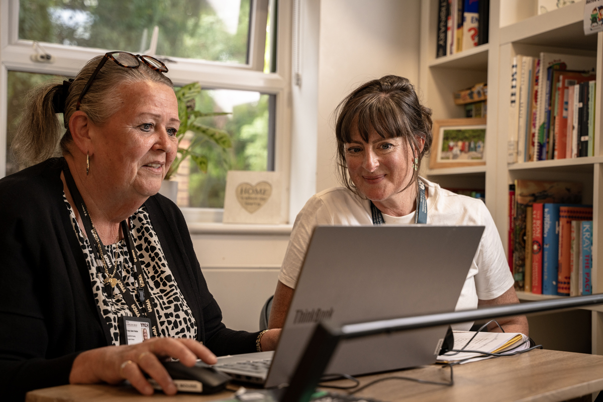 Two members of staff looking at a laptop