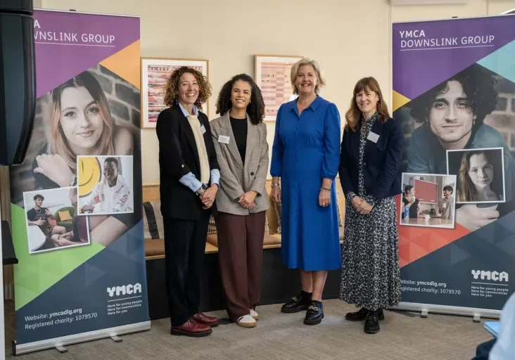 four women stood in front of YMCA DownsLink Group branded banners