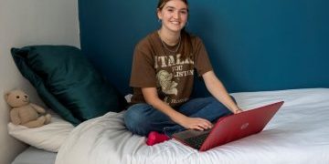 Becky happy image Room sponsorship - Becky sat on bed