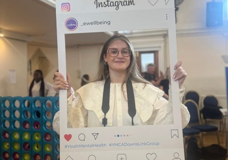 tabs, volunteer photographer, holds a board up that looks like an instagram post and is smiling
