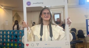 tabs, volunteer photographer, holds a board up that looks like an instagram post and is smiling