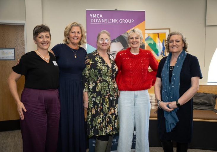 five women standing together and smiling at ymca downslink group event for world mental health day and world homelessness day