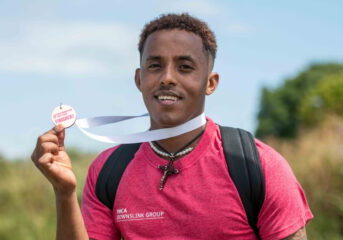 Temesgen smiling holding his medal at the end of the DownsLink Challenge