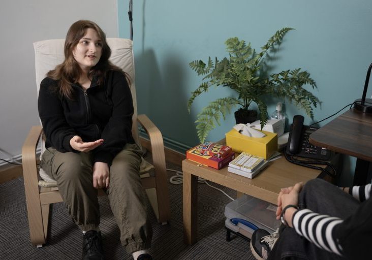 a seated young person talking to another person off-screen