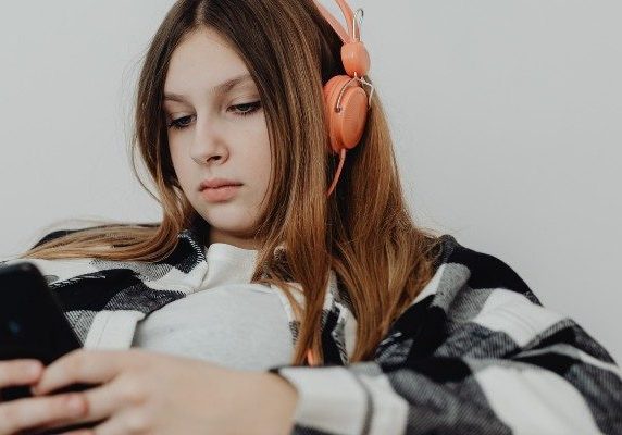 Young person with headphones on looking a mobile phone