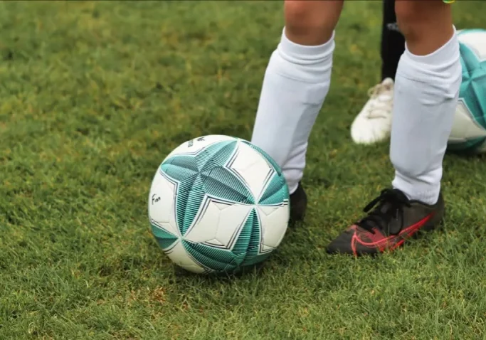 close shot on football and young footballer's leg