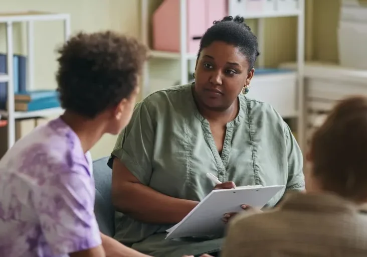 adult with clipboard facing two children seen from back