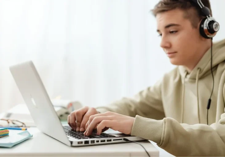 male teen on laptop wearing headset