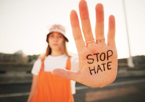 girl holding her hand out. on hand is written stop hate.